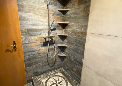 Walk-in Dusche mit Mosaikboden und Eckregalen